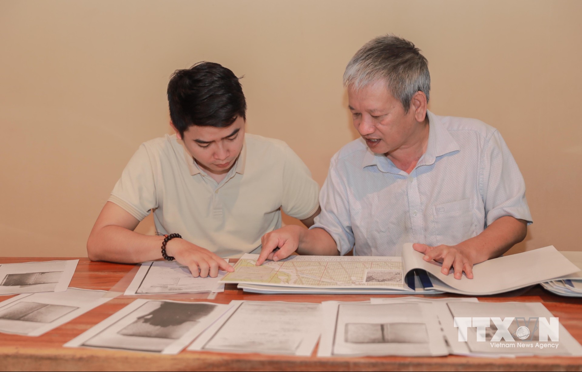 Kiến trúc sư Nguyễn Xuân Thắng (phải) đã dày công "giải mã" các bức ảnh lịch sử từ năm 1968, kết hợp phương pháp chuyển đổi hệ quy chiếu và đối chiếu không gian ảnh để khoanh vùng vị trí rãnh mộ liệt sĩ tại Công viên Lê Thị Riêng. (Ảnh: Phan Phương/TTXVN)
